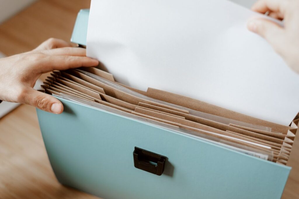 Hands organizing papers in a folder with visible dividers