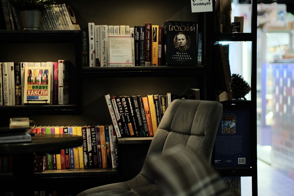 Modern office bookshelf filled with books beside an armchair