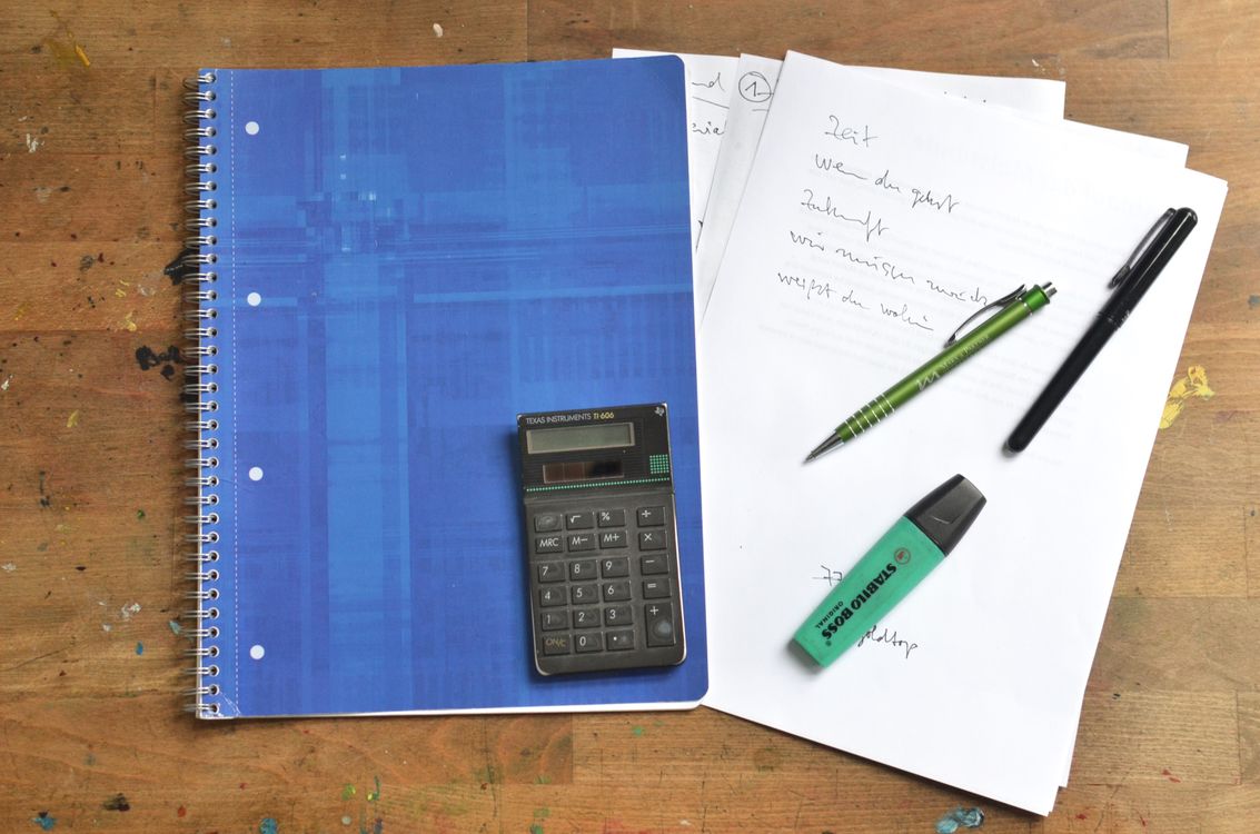 Notebook and office supplies arranged on a wooden desk
