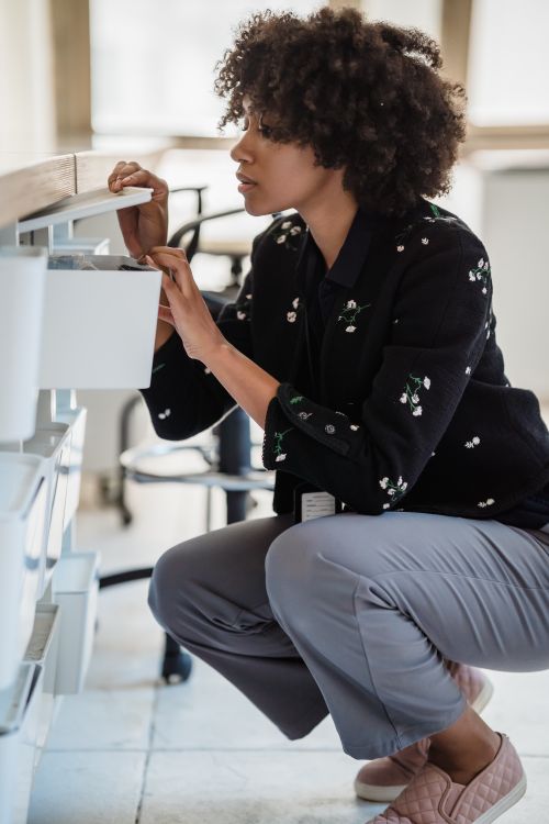 Woman organizing office supplies in a desk drawer