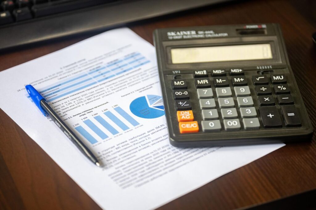 Calculator and financial papers on a wooden office desk
