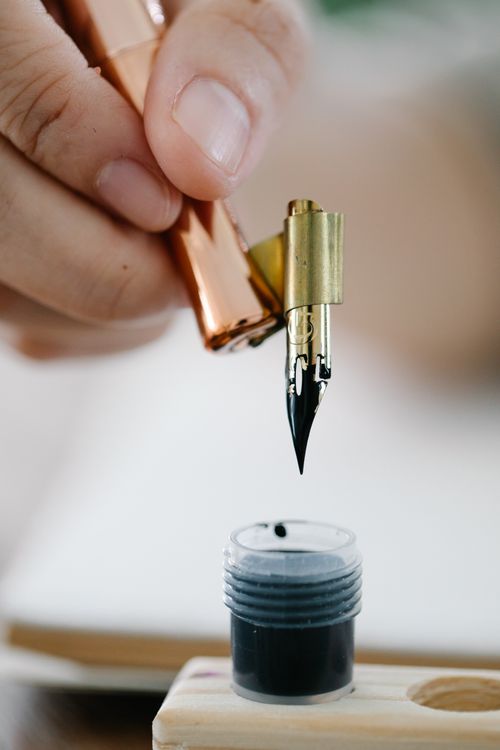 Fountain pen being dipped into an ink bottle
