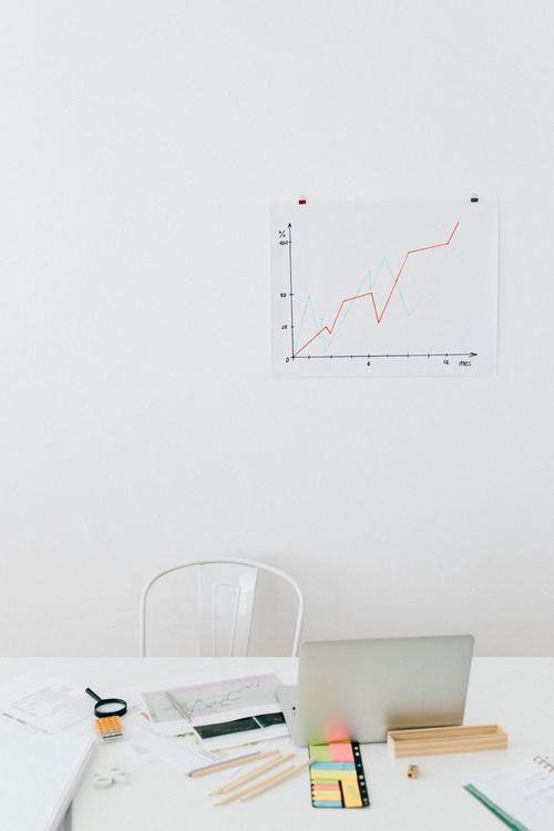Desk setup with graph paper, chart, laptop, and office supplies