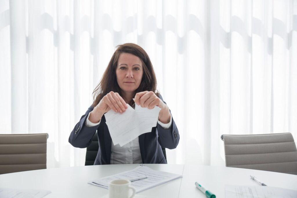 Businesswoman tearing confidential-looking papers at an office desk