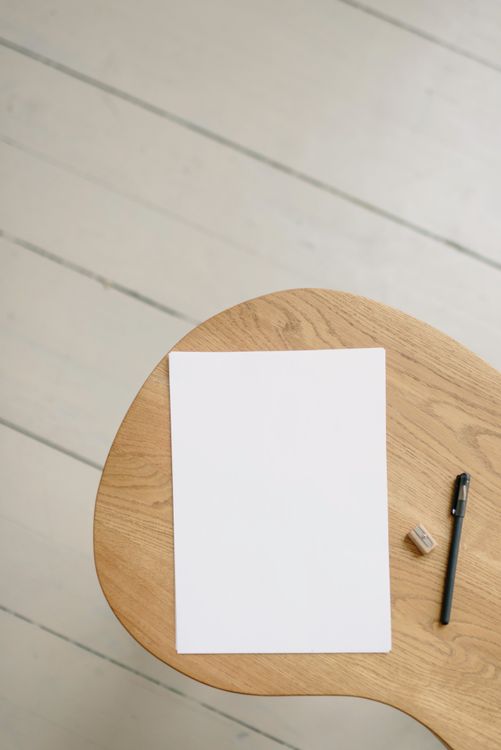 Clean white paper and pen on a minimalist wooden desk