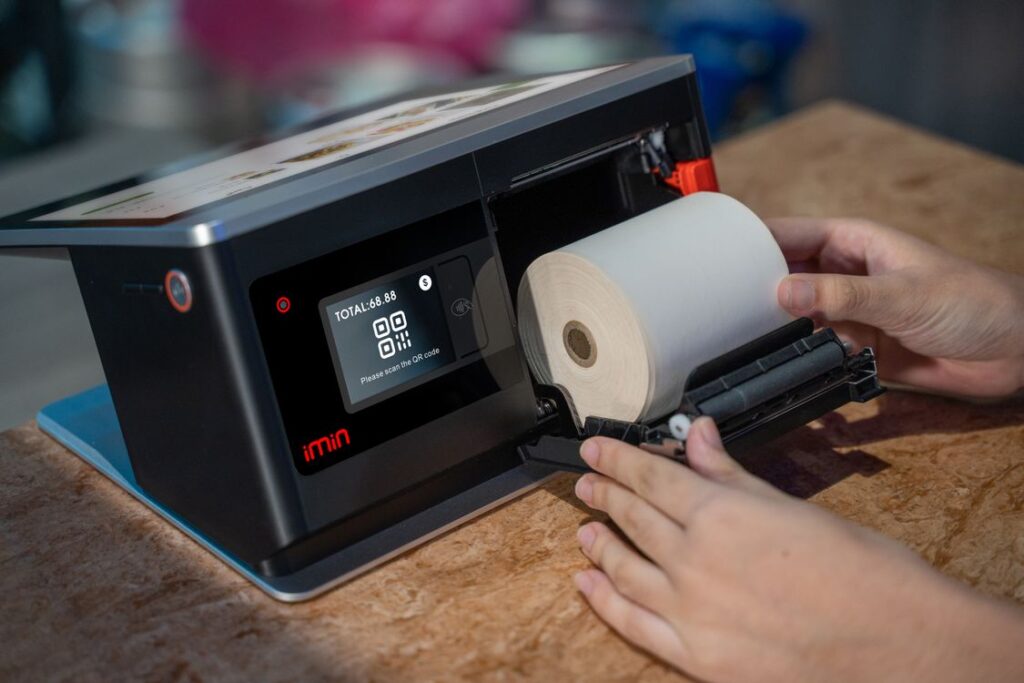 Hands changing a thermal paper roll in a point-of-sale printer