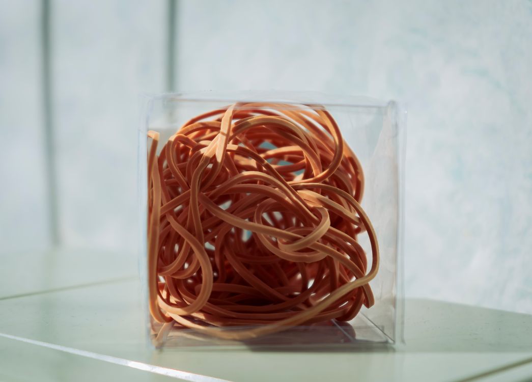 Orange rubber bands neatly stored in a clear container
