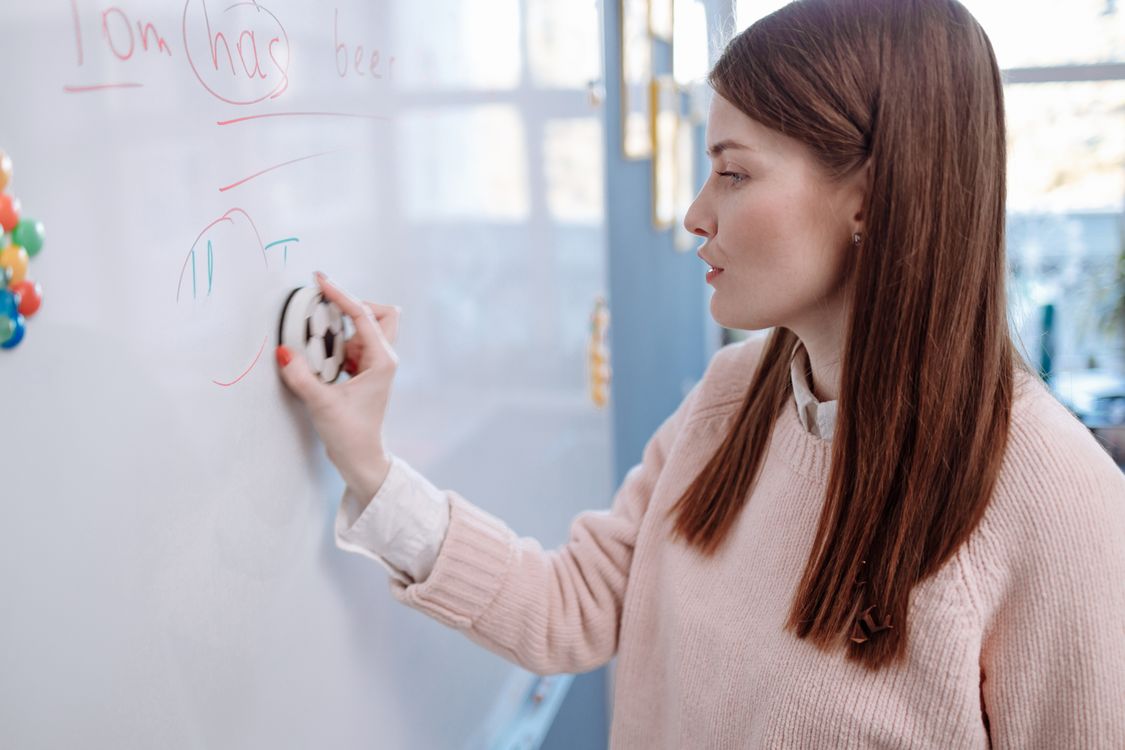Teacher erasing a whiteboard in a bright classroom