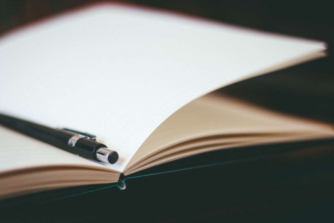 Close-up of a pen resting on an open notebook