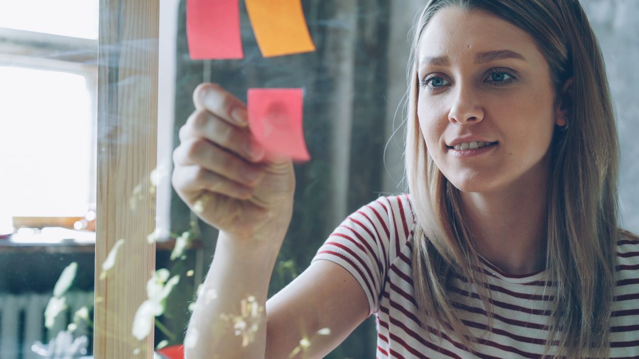 Person organizing colorful sticky notes in a bright office