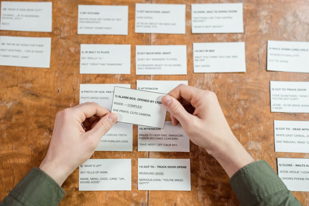 Hands organizing index cards on a desk for studying and planning