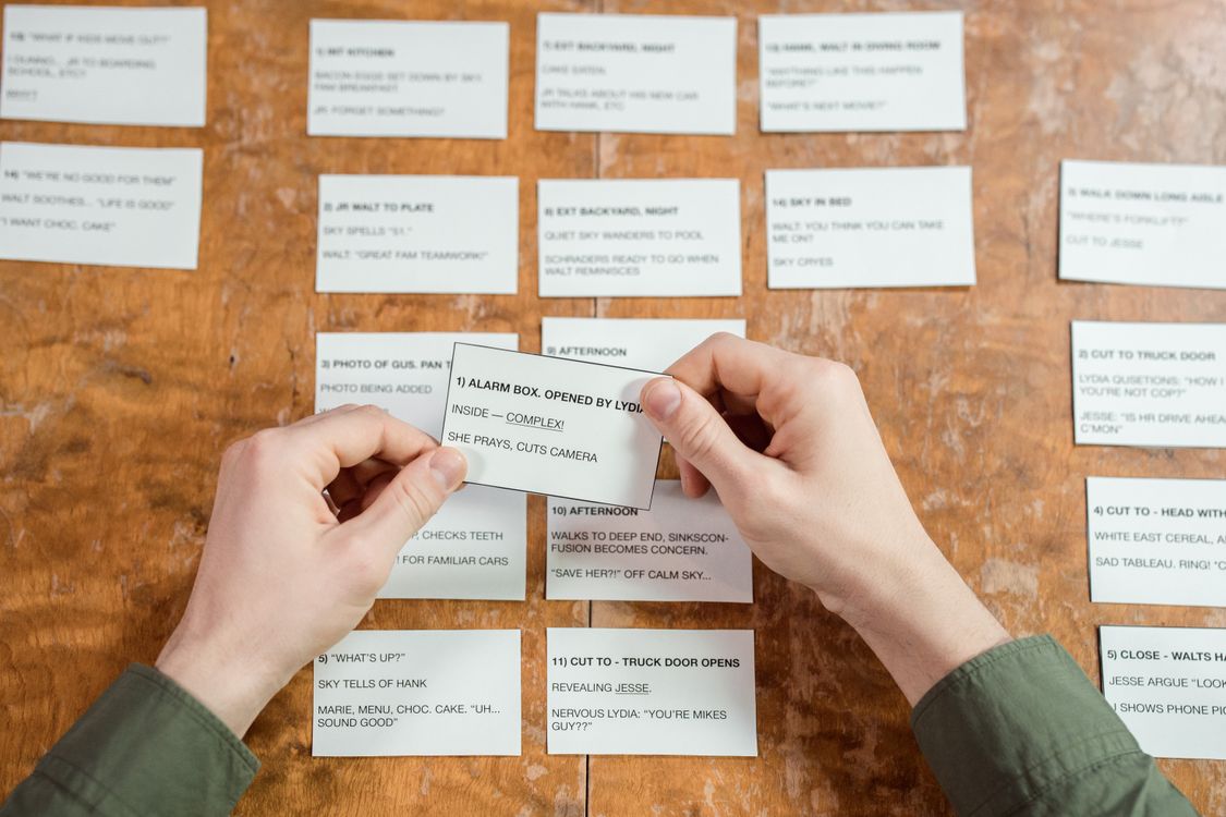 Hands organizing index cards on a desk for studying and planning
