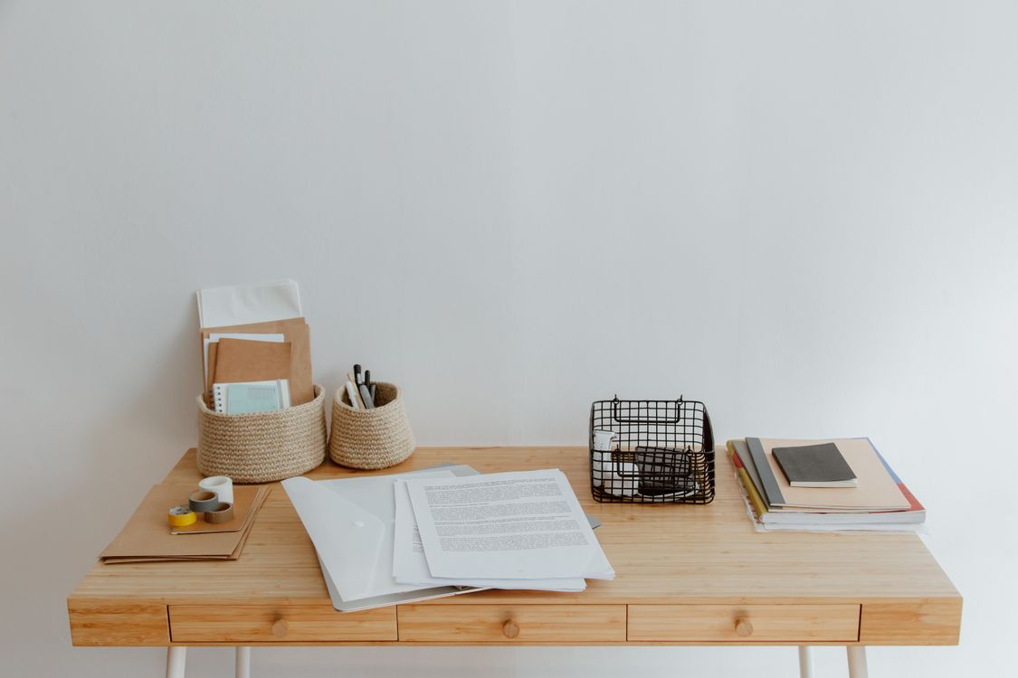 Clean organized home office desk with baskets and stationery