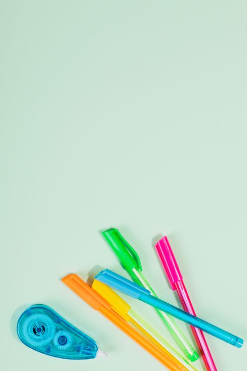 Correction tape with colorful pens on a bright background
