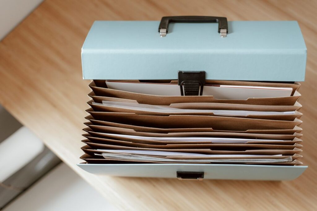 Blue accordion file organizer filled with papers on a wooden desk